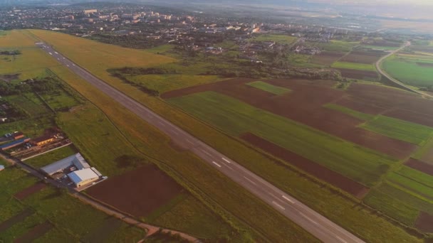Εναέρια θέα του μικρού αεροδρομίου με την απογείωση και το λευκό αεροπλάνο που πετούν πάνω. 4K. - Πλάνα, βίντεο