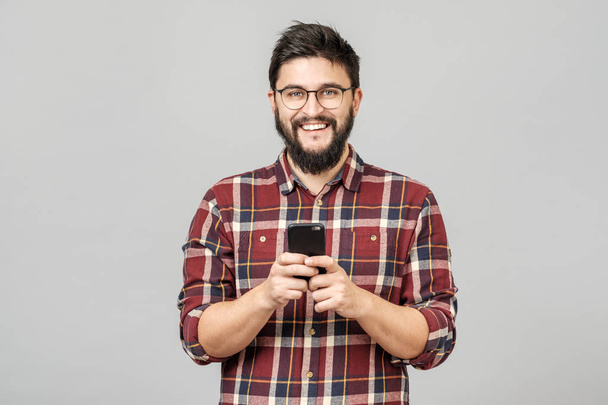Portrait of handsome european man holding telephone while textin - Фото, изображение