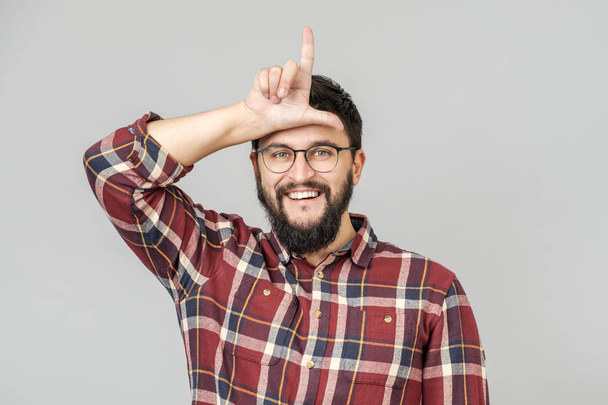 Portrait of happy guy with showing loser sign - Фото, изображение