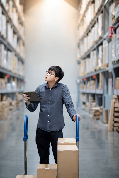 Asian man doing stocktaking on tablet in warehouse - Photo, Image