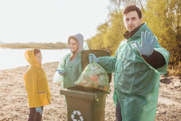 group of volunteers with garbage bags cleaning area near lake - Fotó, kép