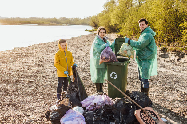 group of volunteers with garbage bags cleaning area near lake - Photo, Image