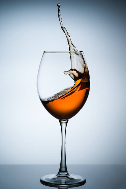Amber wine. A splash of wine in a glass. Liquid in a glass. Traditional wine according to the ancient Georgian technology. Concept with a glass of wine. Copy space. Close up and vertical orientation. - 写真・画像