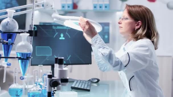 Chemik kobieta analiza próbki za pomocą dużego szkła powiększającego - Materiał filmowy, wideo