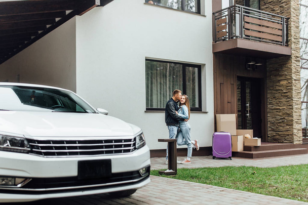 Attractive couple hugging near new white car and home - Fotoğraf, Görsel