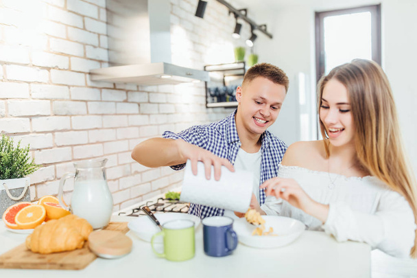 Happy and cheerful young couple at kitchen, focus on foreground - Foto, imagen