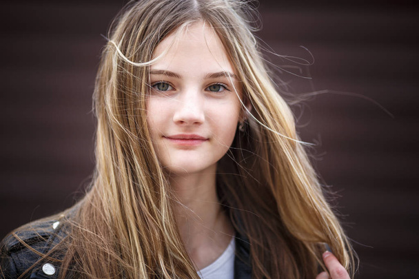close-up portrait of little beautiful stylish kid girl with long flowing hair against a brown striped wall - Fotografie, Obrázek