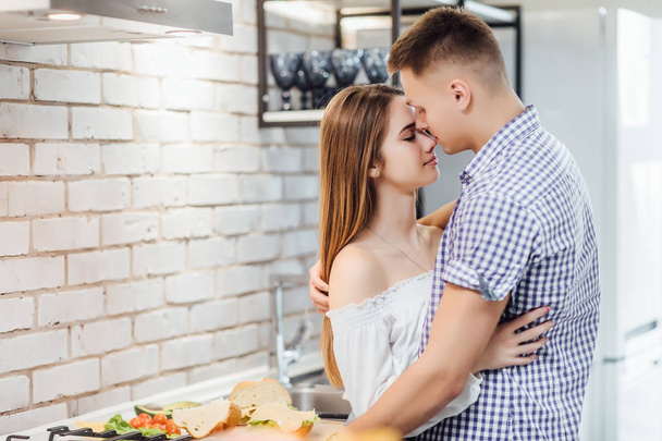 Happy and cheerful young couple at kitchen, focus on foreground - Foto, Imagem