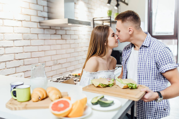 Happy and cheerful young couple at kitchen, focus on foreground - Фото, изображение