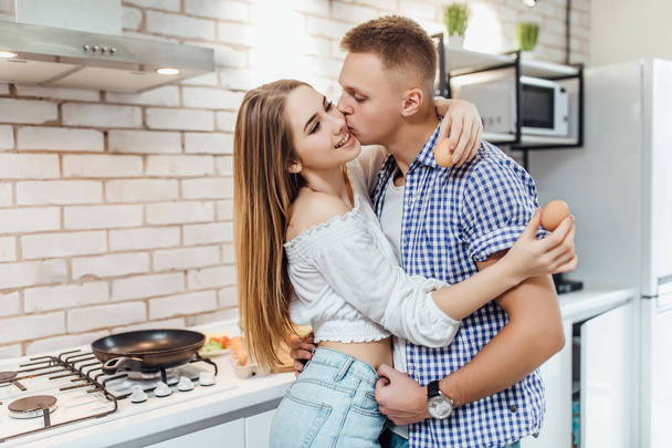 Happy loving couple hugging at kitchen, focus on foreground - 写真・画像