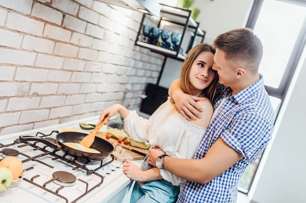 Young beautiful couple cooking at kitchen, selective focus - Foto, afbeelding
