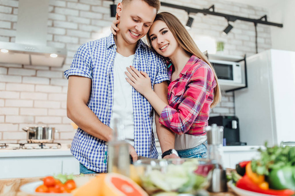 happy young couple preparing food at kitchen together - Фото, зображення