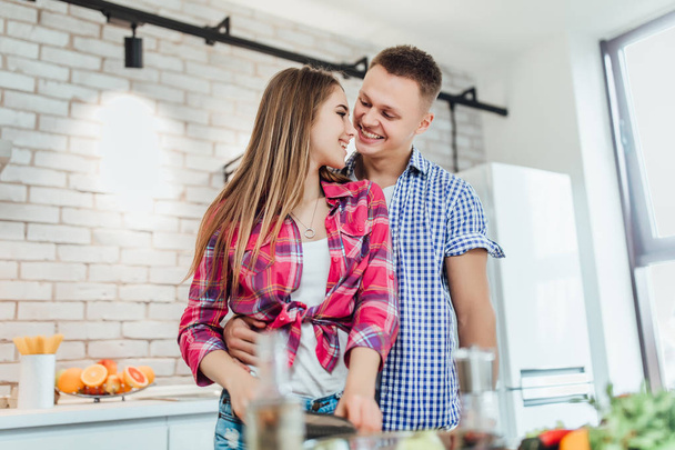 young positive couple preparing food together, focus on foreground - Фото, изображение