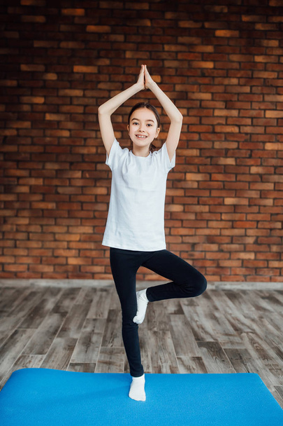 young girl practicing yoga at home, focus on foreground - Фото, изображение