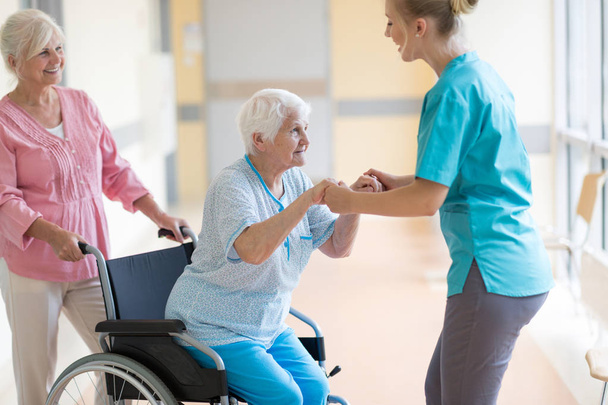 Starsza kobieta na wózku inwalidzkim z córką i pielęgniarką - Zdjęcie, obraz