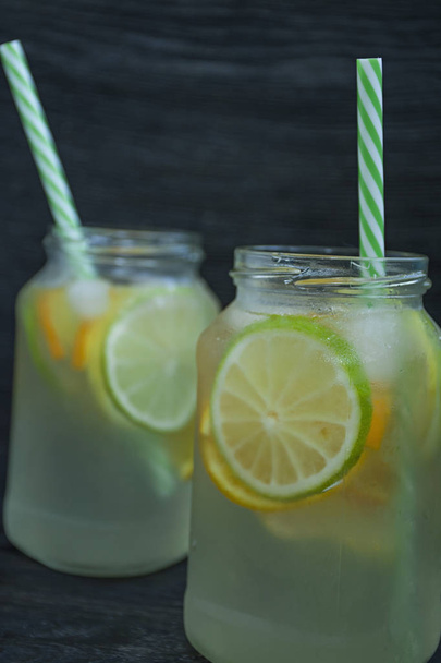 Frissítő nyári ital citrusfélék. Igyál mész, citrom, narancs. Sötét fából készült háttér. - Fotó, kép