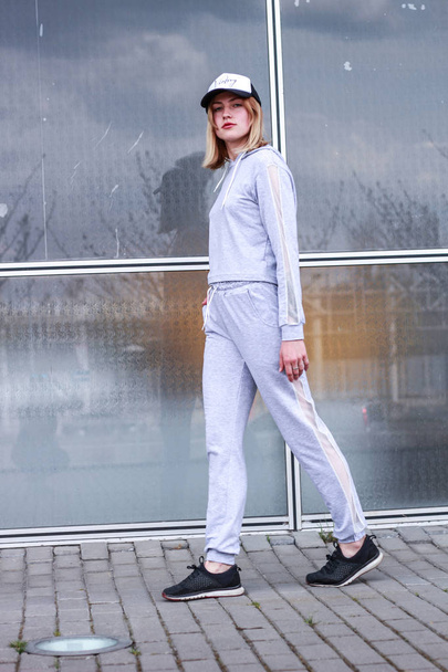 The girl is blonde in a gray sports suit. Street clothing. Sport - Foto, imagen