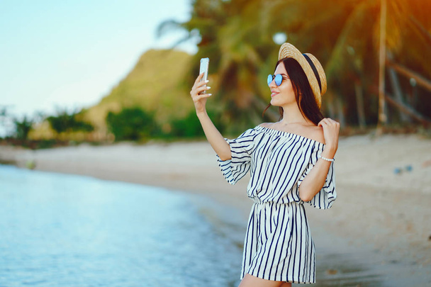 girl waking along the beach using her phone - Foto, Imagen