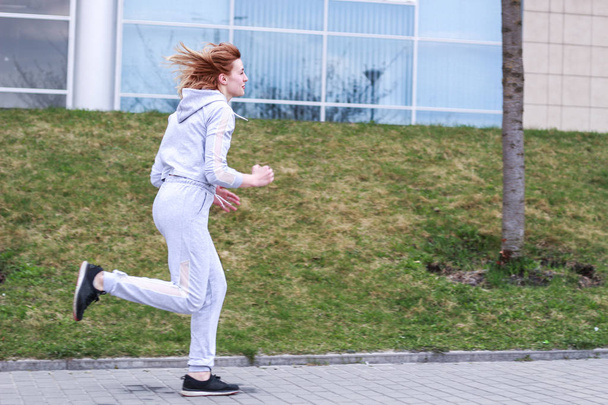 Kız gri spor takım elbiseli sarışın. Sokak kıyafetleri. Spor - Fotoğraf, Görsel