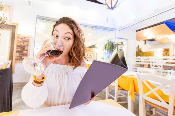 Femme buvant du vin et lisant le menu au restaurant
 - Photo, image