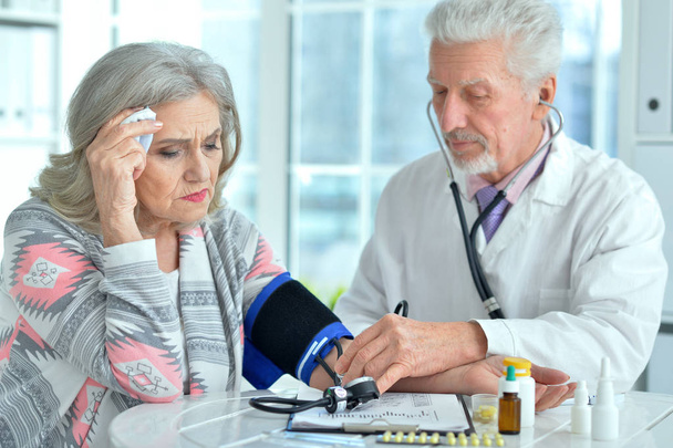 Elderly doctor measuring blood pressure - Фото, зображення
