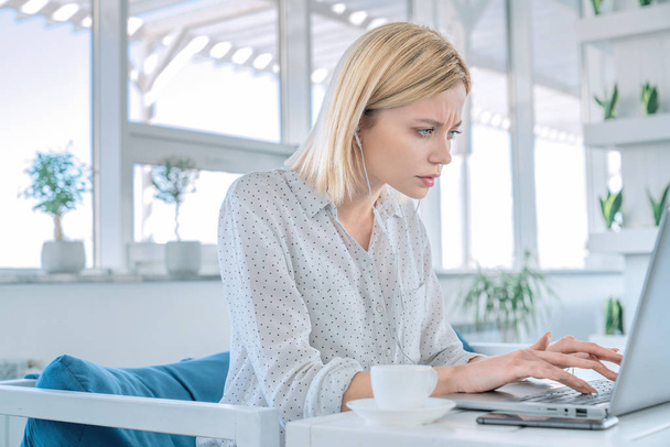 Знімок бізнес-леді, що працює на ноутбуці, сидячи на своєму робочому місці з чашкою кави та мобільним телефоном на ньому
 - Фото, зображення