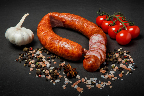 нарезанный круг копченой колбасы с чесноком и вишней из помидоров
 - Фото, изображение