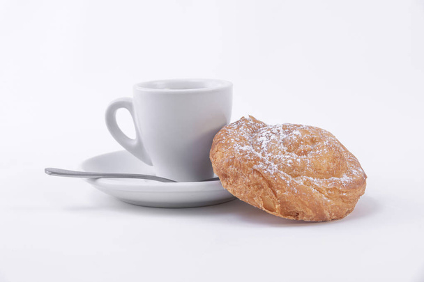 Une tasse de café chaud et un rouleau de pâte feuilletée avec du sucre en poudre
 - Photo, image