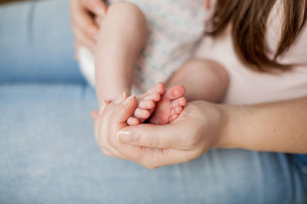Close-up. As pernas do bebezinho nos braços das mães. Maternidade
. - Foto, Imagem