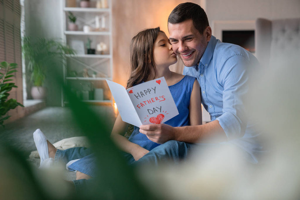 Happy Father's Day! Cute little girl kissing her father and give him gift postcard - Фото, изображение