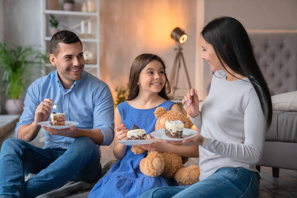 Feliz familia joven comiendo juntos pastel en casa. Familia alegre
 - Foto, imagen