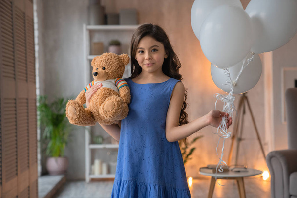 Happy cute little girl with teddy bear and air balloons in her hand - Fotó, kép