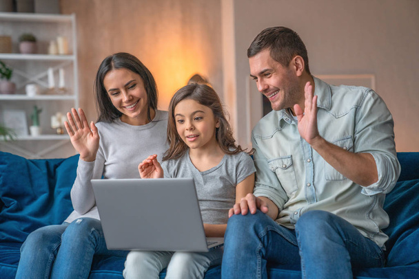 Happy family waving hands looking at web camera using laptop for - Фото, зображення