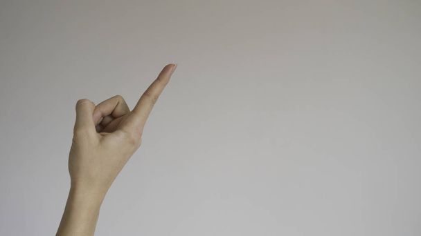 Açık gri arka planda bir kadının işaret parmağı - Fotoğraf, Görsel