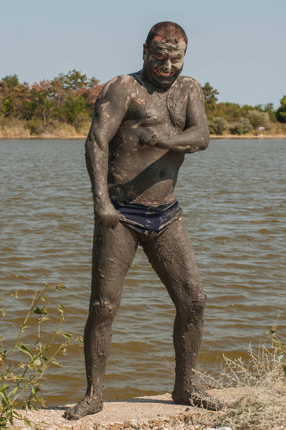 Karadeniz kıyısında Mud Spa tedavileri. Bir adam Bulgaristan'da tatil yapıyor. Tam büyüme kirli erkekler.  - Fotoğraf, Görsel