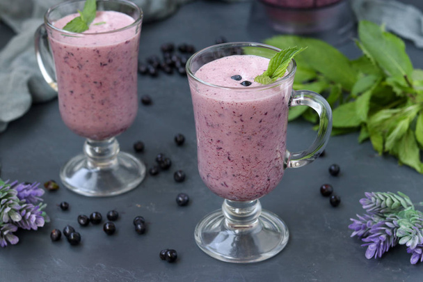 Výživný koktejl s jogurtem a borůvkami umístěnými v brýlích na tmavém pozadí, zdravé stravování - Fotografie, Obrázek