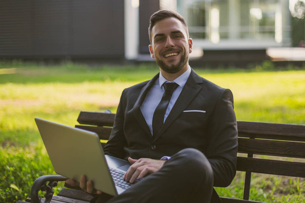 Elegant businessman using laptop while sitting outdoor.Toned image. - Fotó, kép