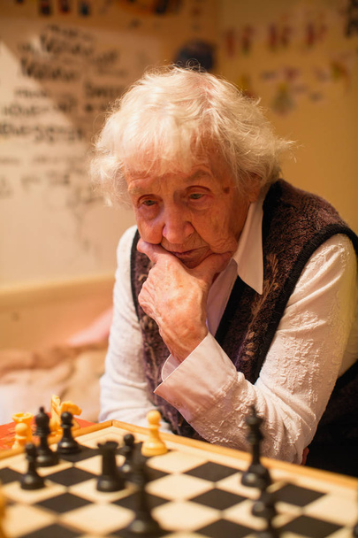 Una anciana está jugando ajedrez.. - Foto, Imagen