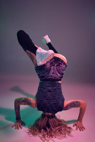joven hermosa rubia gimnasta chica en terciopelo azul botín pantalones cortos y negro medias de pie boca abajo sobre rosa fondo
 - Foto, Imagen
