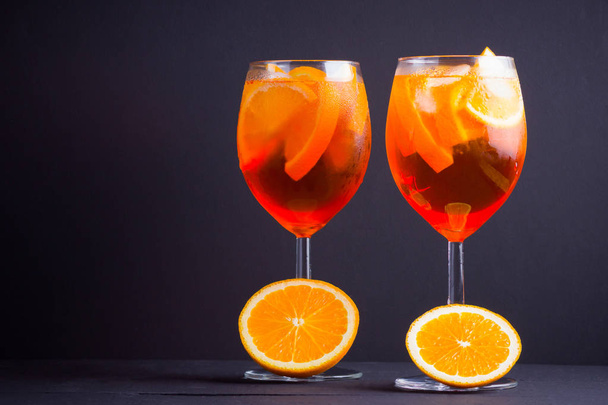 Cocktail aperol spritz on black background. Summer alcohol cocktail with orange fruit and fresh mint. Italian cocktail aperol spritz on wooden boards - Zdjęcie, obraz