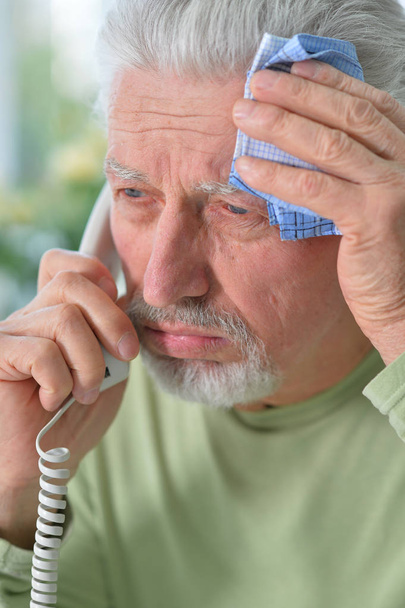 Portrait of sad sick senior man calling doctor  - Фото, изображение