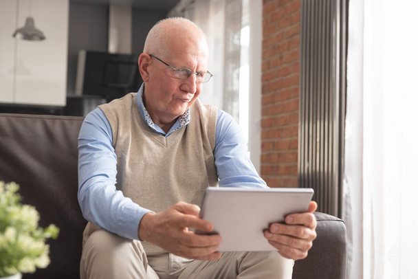 Senior man using digital tablet in living room - Zdjęcie, obraz