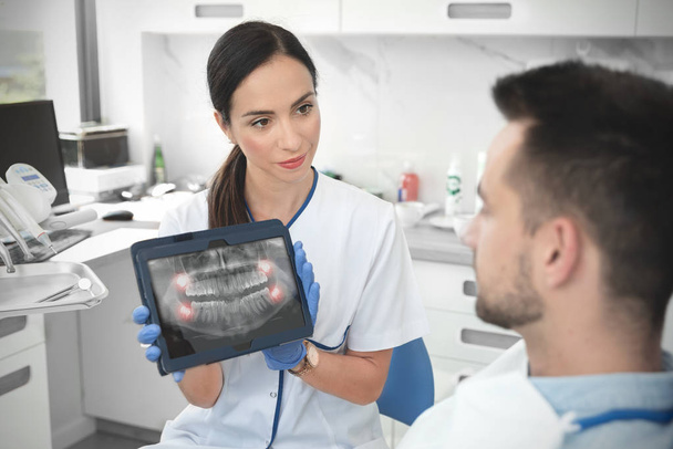 Dentista feminina mostrando raios-x dos dentes em comprimido
 - Foto, Imagem