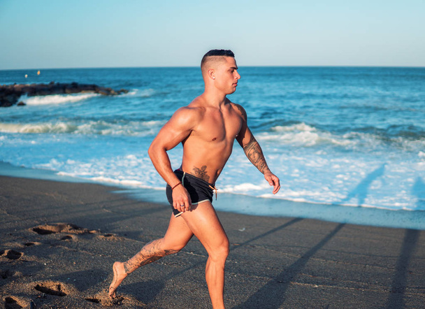 Τατουάζ bodybuilder σέξι αρσενικό προπονητής στην παραλία. - Φωτογραφία, εικόνα
