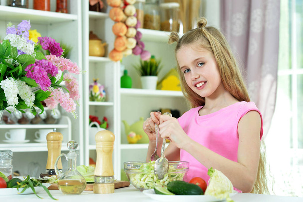Χαριτωμένο κορίτσι προετοιμασία νόστιμα φρέσκια σαλάτα στην κουζίνα - Φωτογραφία, εικόνα