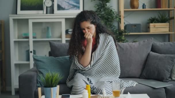 Zoom-in of unhealthy girl coughing and wiping running nose in apartment - Materiał filmowy, wideo