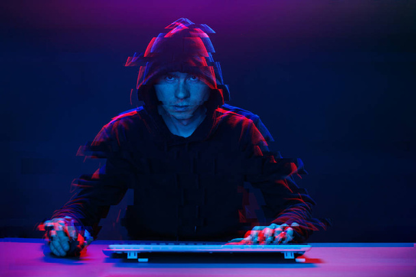 Hacker no capô trabalhando com computador digitando texto no quarto escuro. Imagem com efeito de falha
 - Foto, Imagem