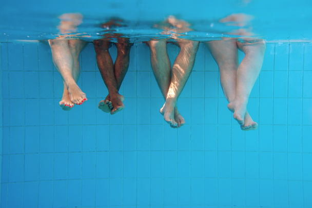 four people legs underwater in the swimming pool. Friends. Party. Summer. Vacation and sport concept. - Φωτογραφία, εικόνα