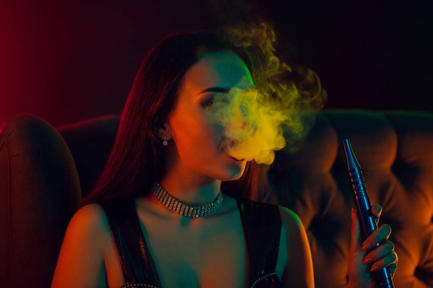 Sexy modello bruna è fumare un narghilè espirare un fumo in un night club di lusso
. - Foto, immagini