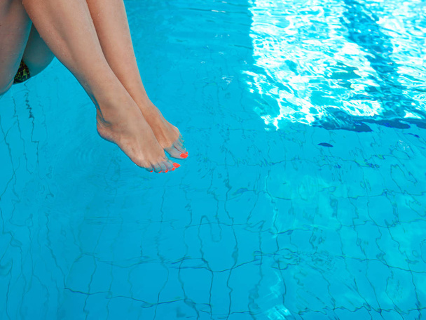 adulto blanco caucásico piernas de mujer europea con naranja pedicura ultravioleta bajo el agua en la piscina. Verano. Concepto de vacaciones y deporte
. - Foto, imagen